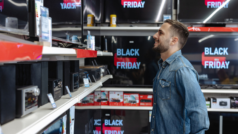 A man looking at TVs that all say "Black Friday" on the screens