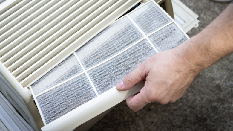 A person replaces a filter in an air conditioner
