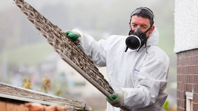 Man removing an asbestos panel from a home