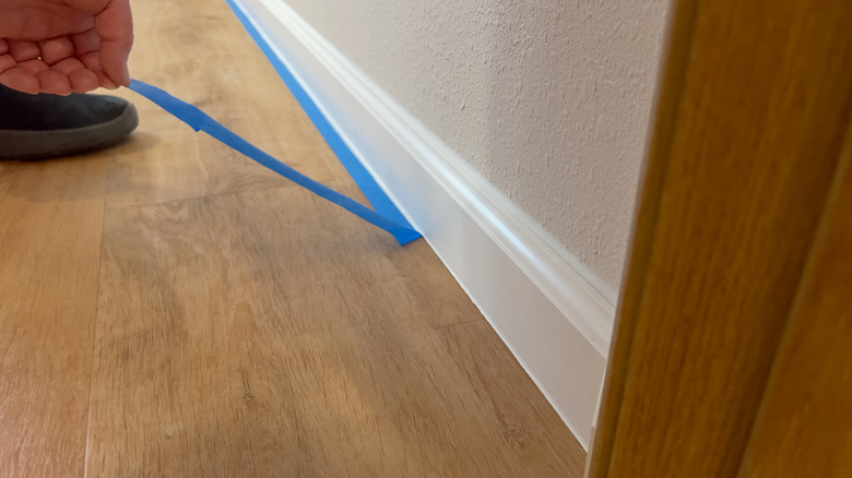 Hand removing blue painter's tape from wall