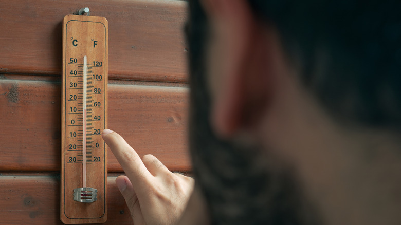 Man checking outdoor temperatures with thermometer