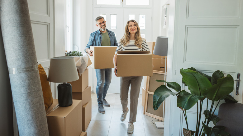 Couple carrying boxes into a new home
