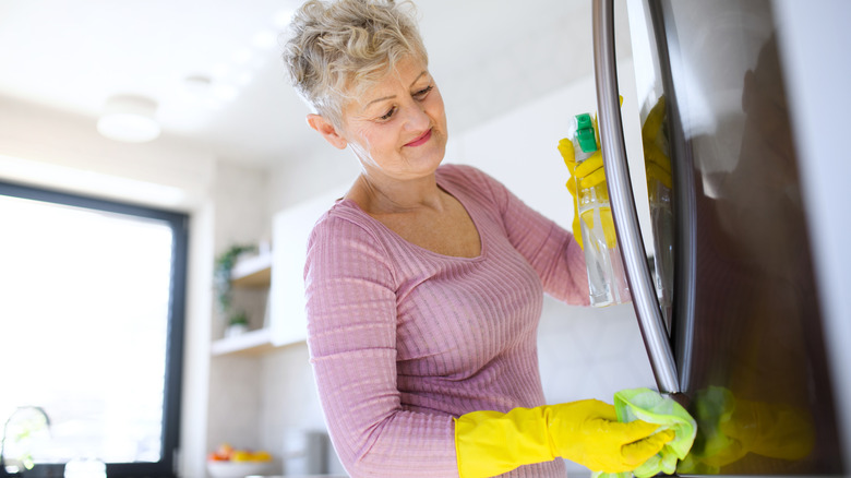 Woman wipes down the handles of a fridge