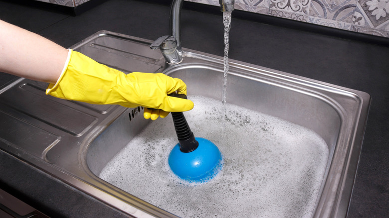Homeowner using a plunger on a sink
