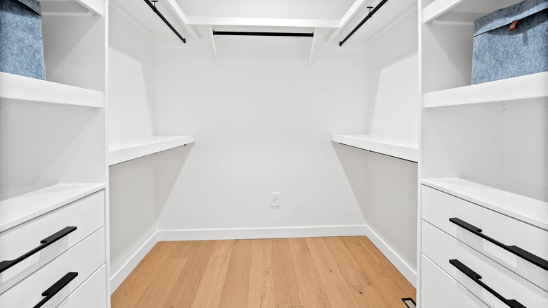 An empty walk-in closet with shelves, railings, and drawers