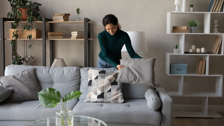 woman arranging pillows on couch