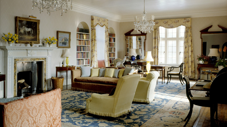 Old money style interior decor in the living room, velvet couches, heavy drapery, crystal chandeliers, and artwork on the wall.