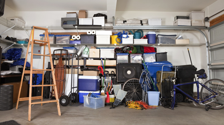 A cluttered garage with items on the floor and shelves