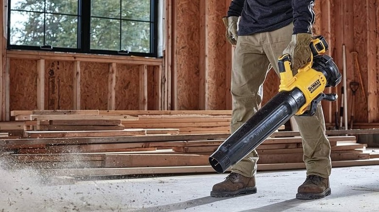 A person using a DeWalt leaf blower in a garage