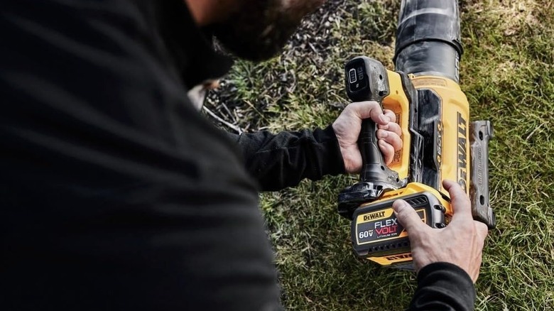 A person changing the battery on a 60V DeWalt leaf blower