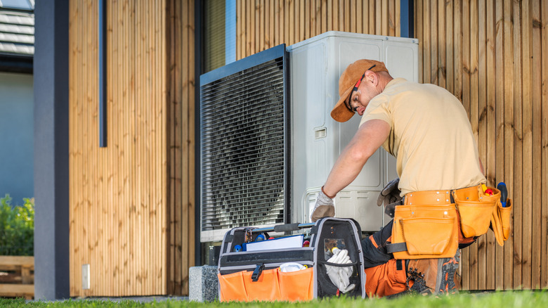 A technician works on a residential HVAC unit outside.