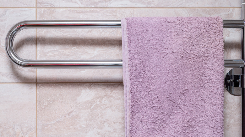 A towel hangs on a chrome heated towel rail