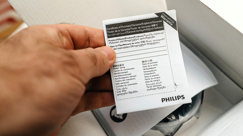 A man holding a paper warranty for his appliance.