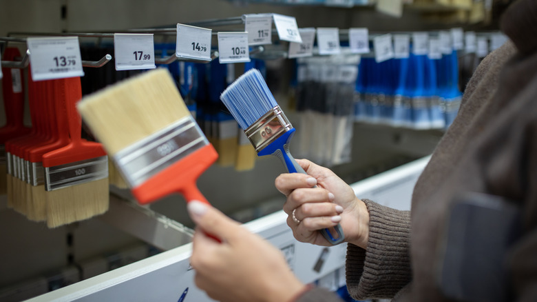 Customer comparing two paint brushes in a hardware store