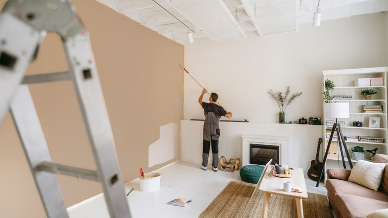A person paints the wall of a living space