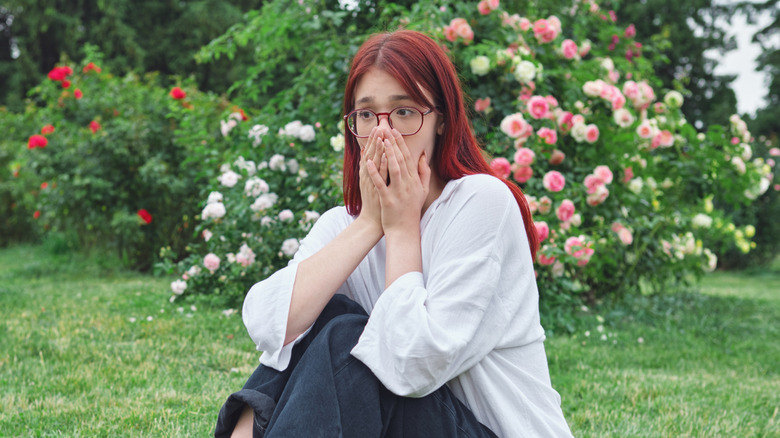Woman covering her nose while sitting in garden