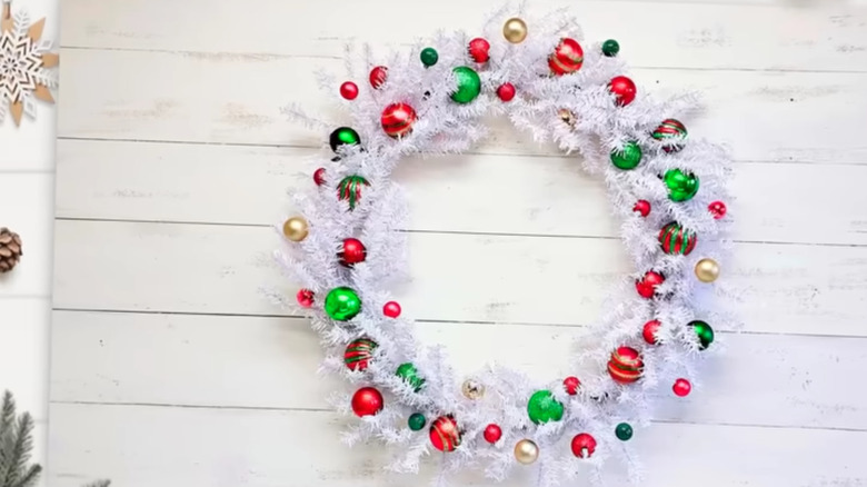 A pretty white wreath made from Dollar Tree supplies and adorned with red, green, and fold baubles