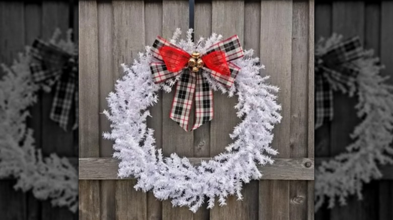 A large wreath made using a hula hoop and adorned with a white garland and a large bow