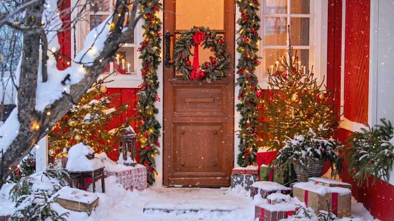 A Christmas wreath on the front door surrounded by garlands and other festive decor
