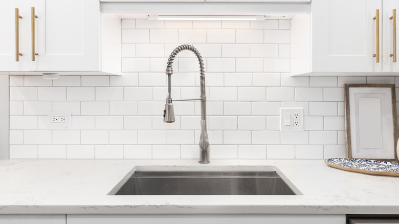 Kitchen sink with white tile backsplash