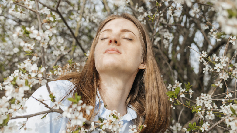 Woman relaxing smelling white flowering trees in garden