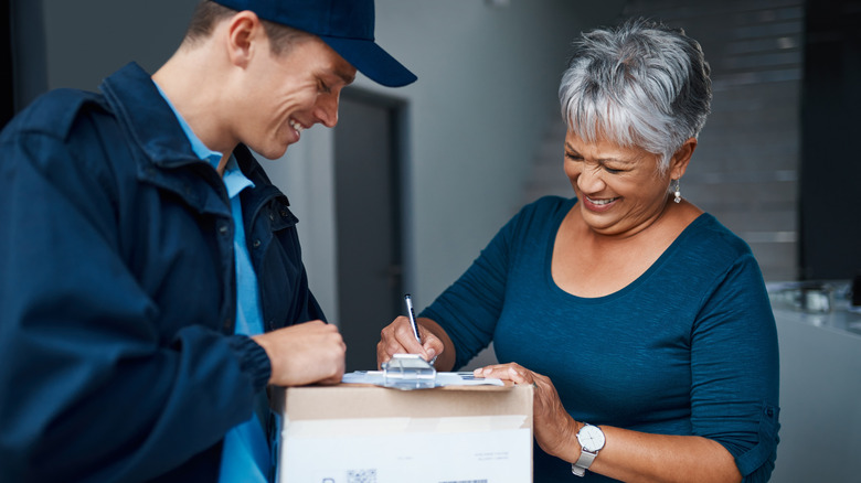 Package, delivery man and woman with clipboard for signature, safety compliance or proof of shipment. Courier service, worker or senior customer with checklist of parcel, postage or ecommerce at home
