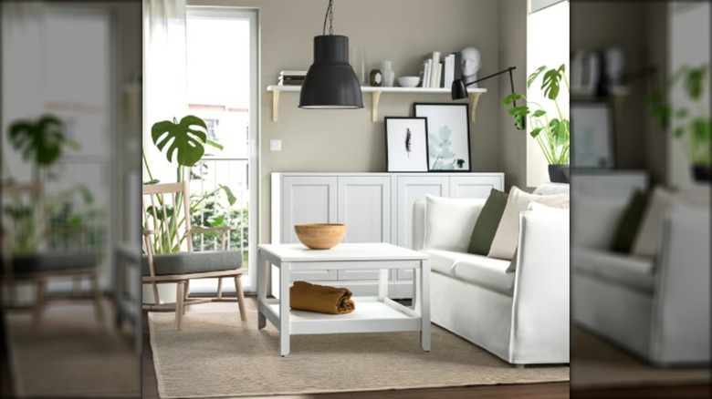 A neutral living room staged with IKEA furniture including a white love seat, white coffee table, and beige area rug.