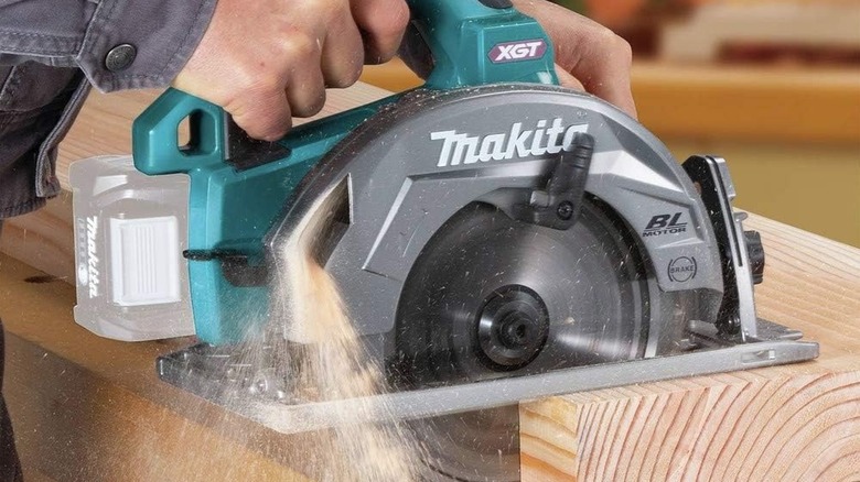 Person using a Makita circular saw on a piece of wood