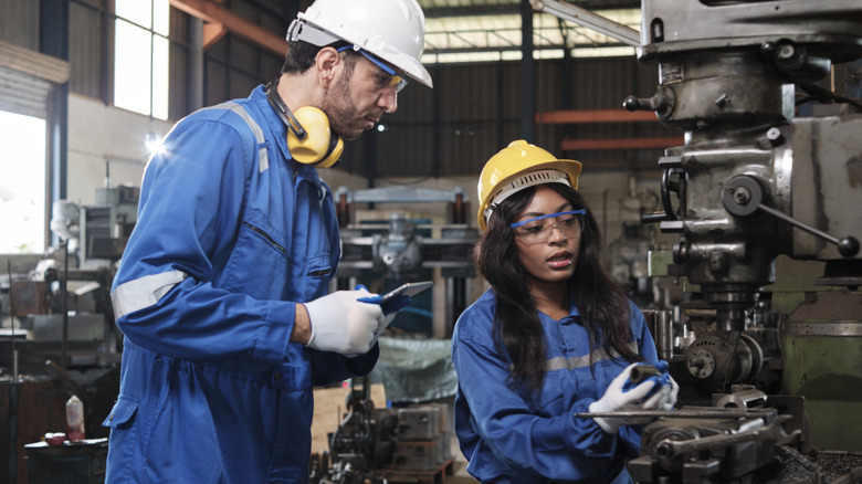 Two workers operate machinery in a workshop