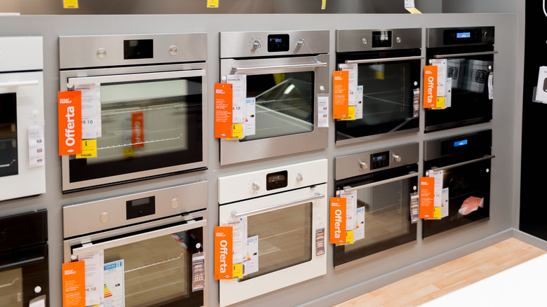 A variety of wall ovens in a row inside of an IKEA showroom.