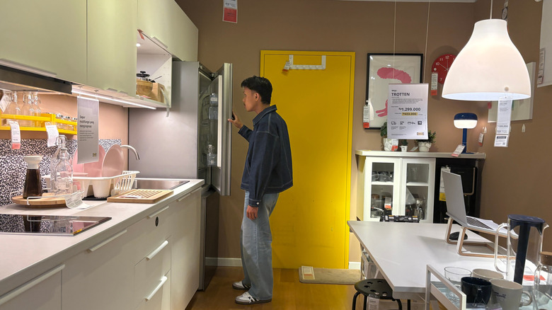 Shopper looking inside a refrigerator in a kitchen display inside an IKEA store