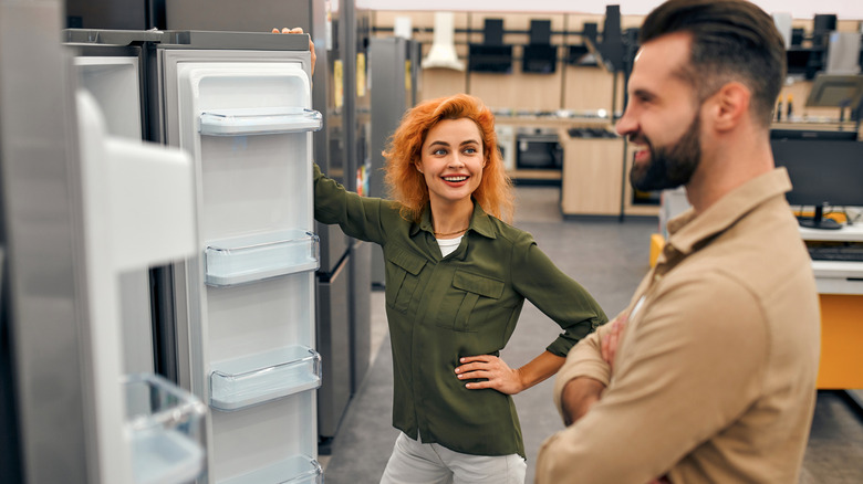 Two people shopping for a new fridge in a store