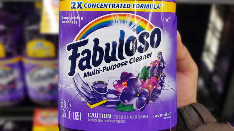 A closeup of a Fabuloso bottle in someone's hands with more in the background. All lavender-scented