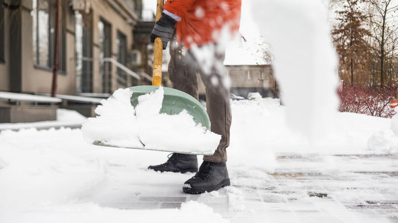 A person shoveling snow from a sidewalk.