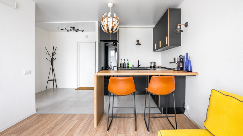 Orange bar stools under small kitchen bar