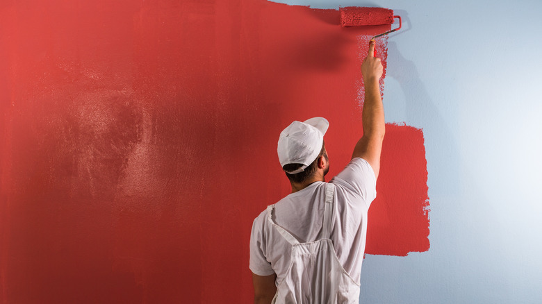 man painting wall bright red
