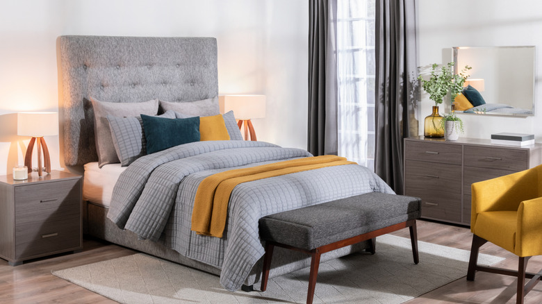 A gray, green, and mustard bed with a patterned blanket on top