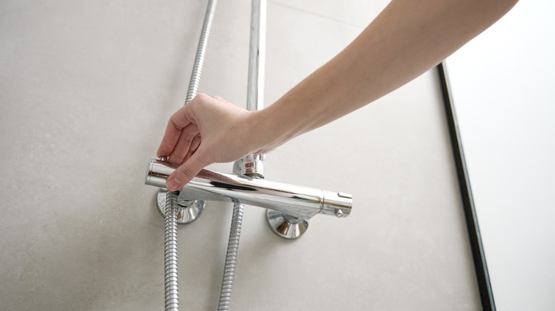 Hand turning on shower faucet