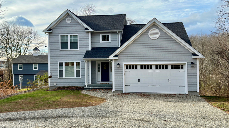 A two-story gray home with a gravel driveway