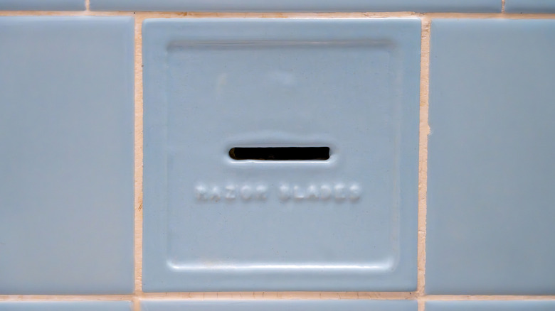 An old razor blade slot on a bathroom wall.