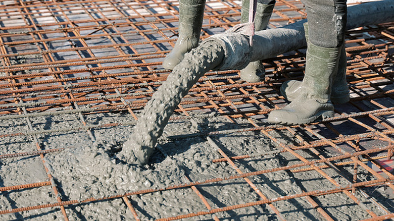 People pouring concrete over rebar to form a house foundation