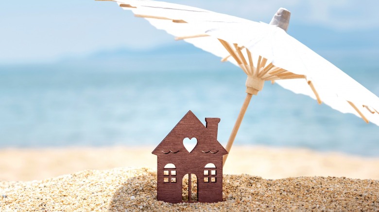 tiny cutout house on beach with umbrella