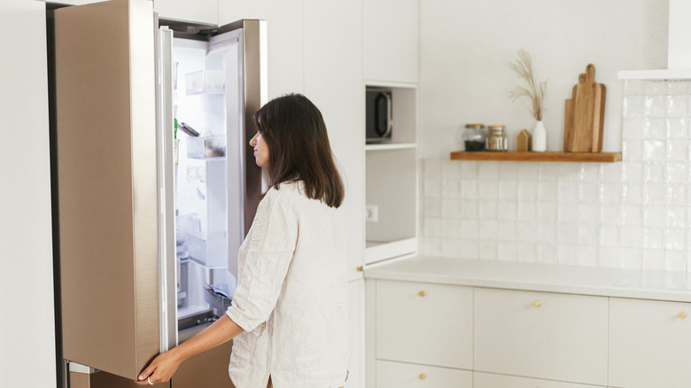 Woman looking inside of an opened refrigerator