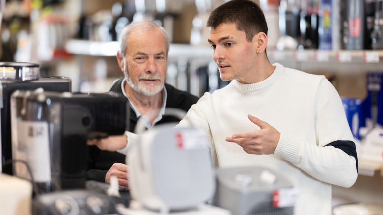 Two men talking over buying a smaller appliance like a coffee grinder or coffee pot