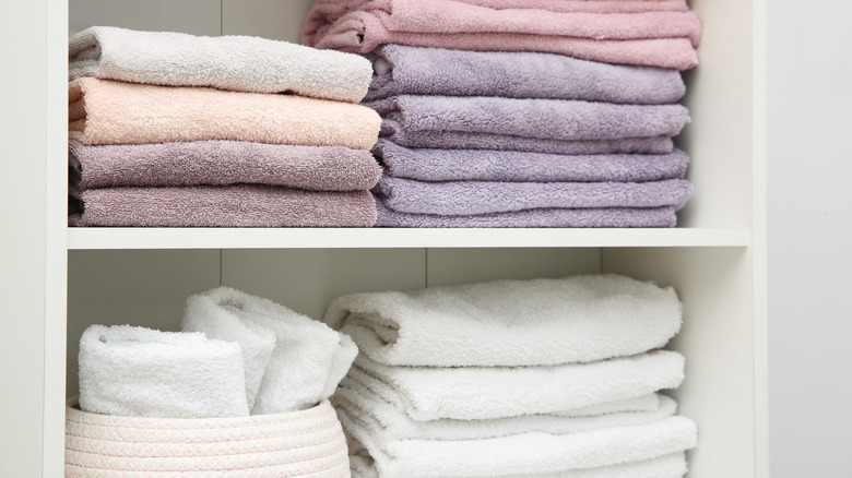 A linen shelf with microfiber towels on top and cotton towels below