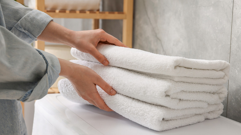 Woman reaches for a stack of folded cotton towels