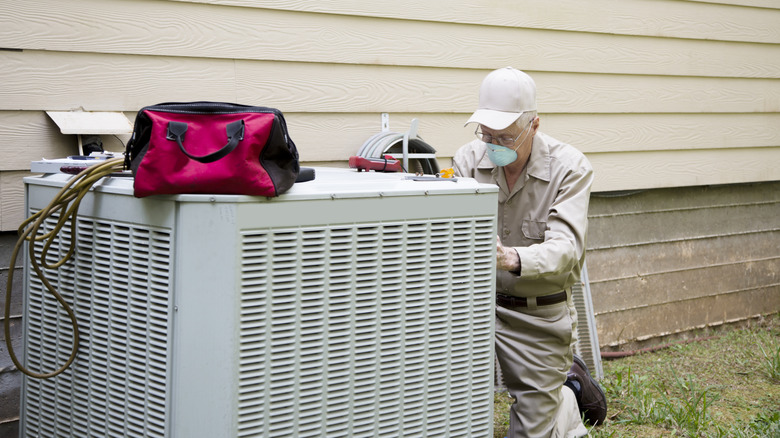 Repair man servicing outdoor AC unit