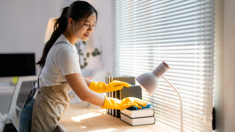 Woman wearing yellow gloves organizing desk in home office