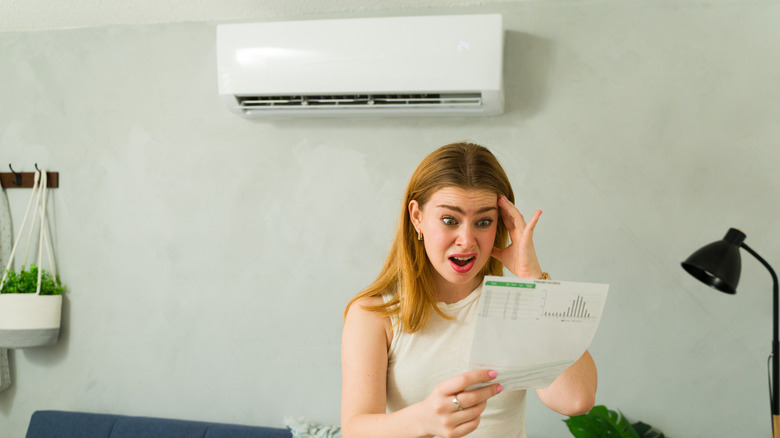 Stressed woman holding an electricity bill in her hand