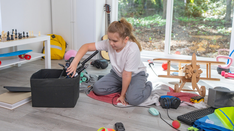 A child playing on the ground with toys scattered around them